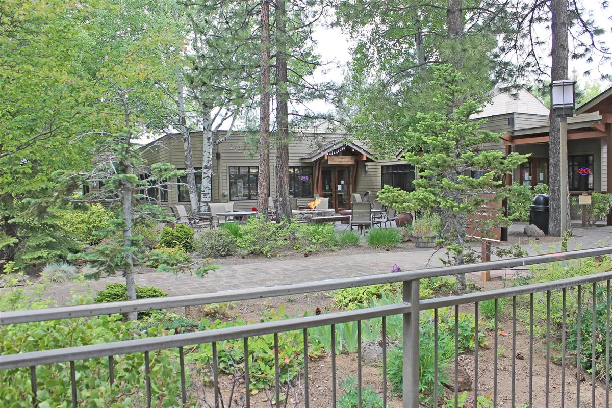 This exterior image showcases a wooden deck area surrounded by lush greenery, with a pathway leading to the entrance. The deck exudes tranquility and offers an inviting spot for guests to relax outdoors, enjoy morning coffee, or share an intimate evening together.